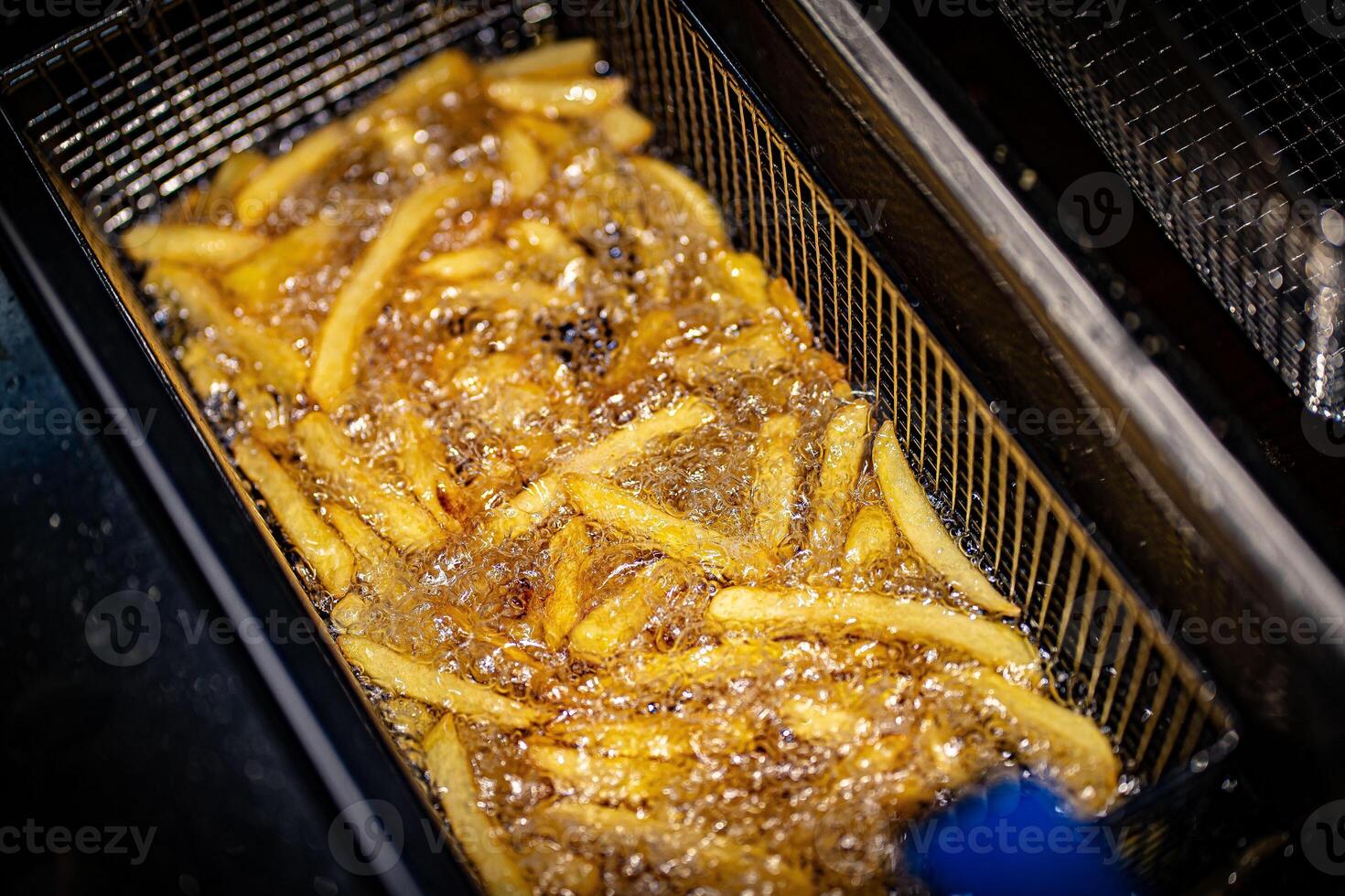 French fries cooking. Grid with strips of potato lowered into boiling oil. The concept of fast food, delicious food, restaurant photo