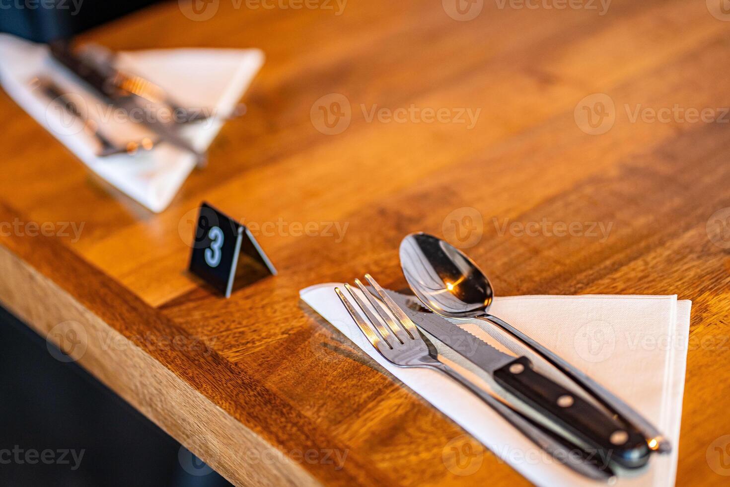 Modern trendy wooden silver appliances - fork and knife on a wooden serving table in the restaurant with a table number photo