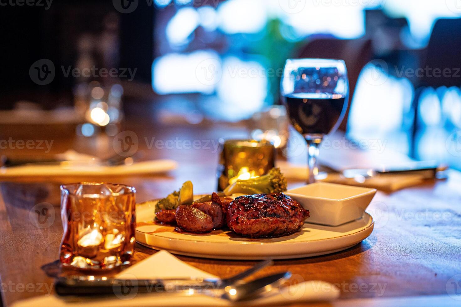 Beef steak meat with vegetables and sauce served with red wine and candles photo