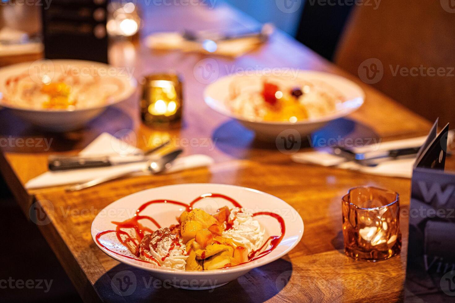 split ice cream with syrup and strawberry on white plate, side view. Chocolate, strawberry and vanilla ice cream scoops on plate, summer dessert photo