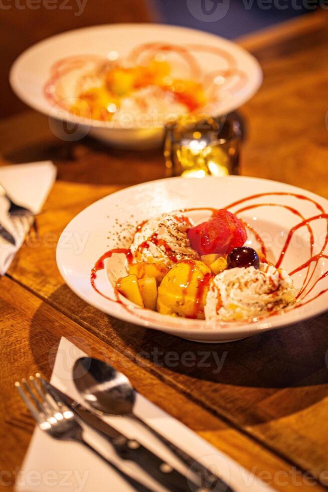 split ice cream with syrup and strawberry on white plate, side view. Chocolate, strawberry and vanilla ice cream scoops on plate, summer dessert Vertical photo