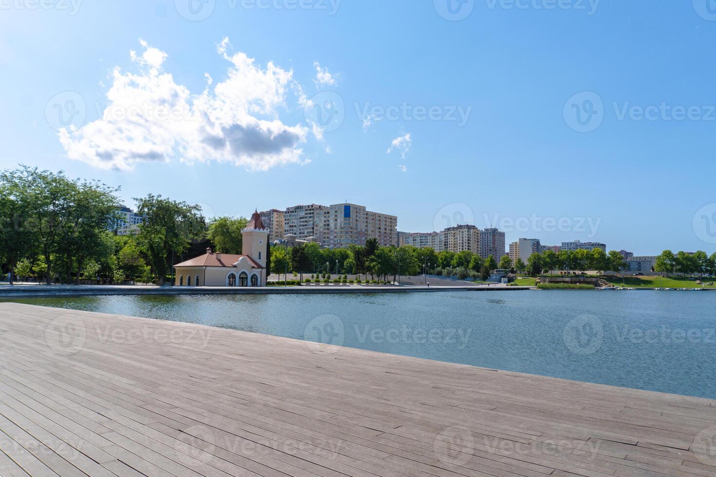 a wooden boardwalk along a lake with buildings in the background photo