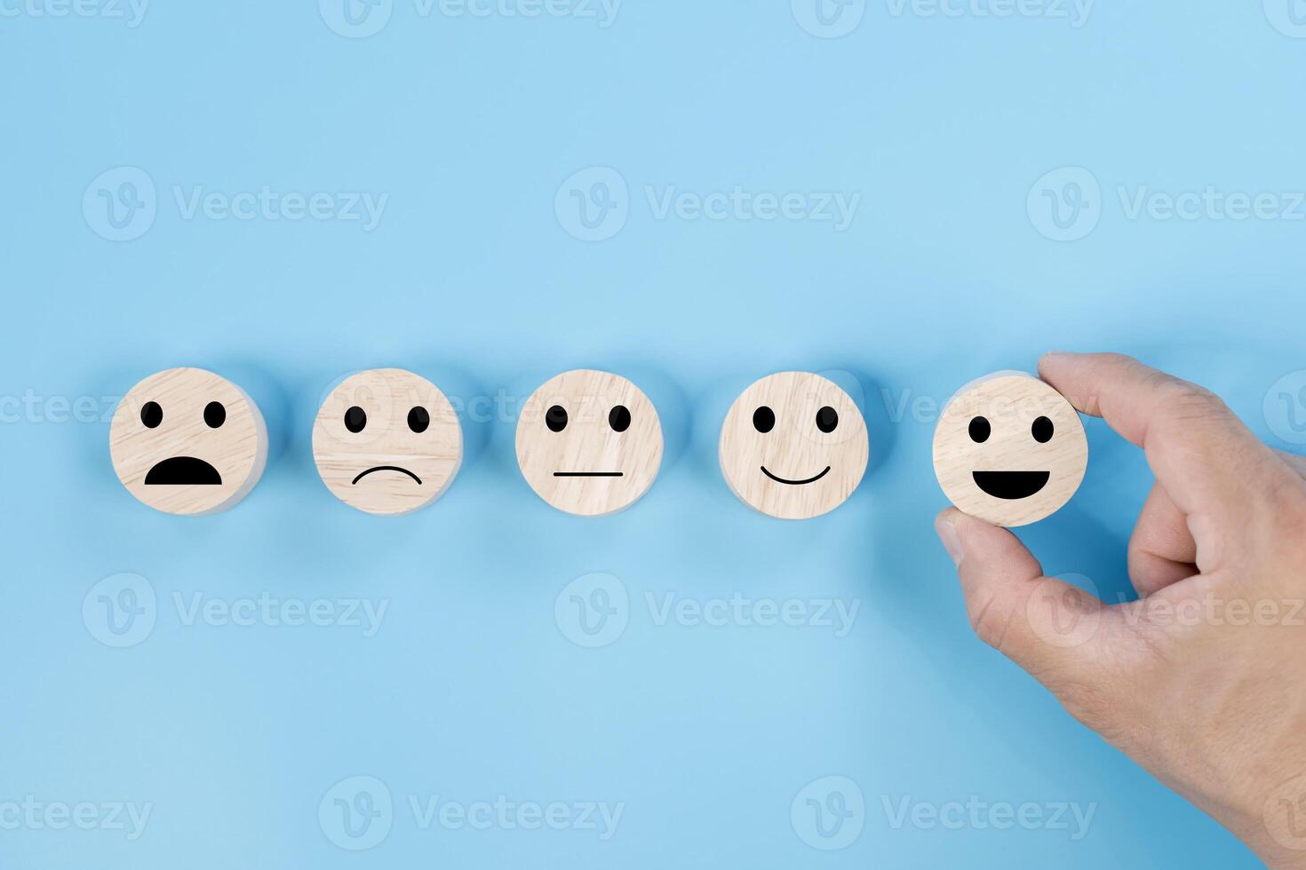 Hand holding smile face symbol on wooden cube blocks on blue background. Customer service evaluation photo