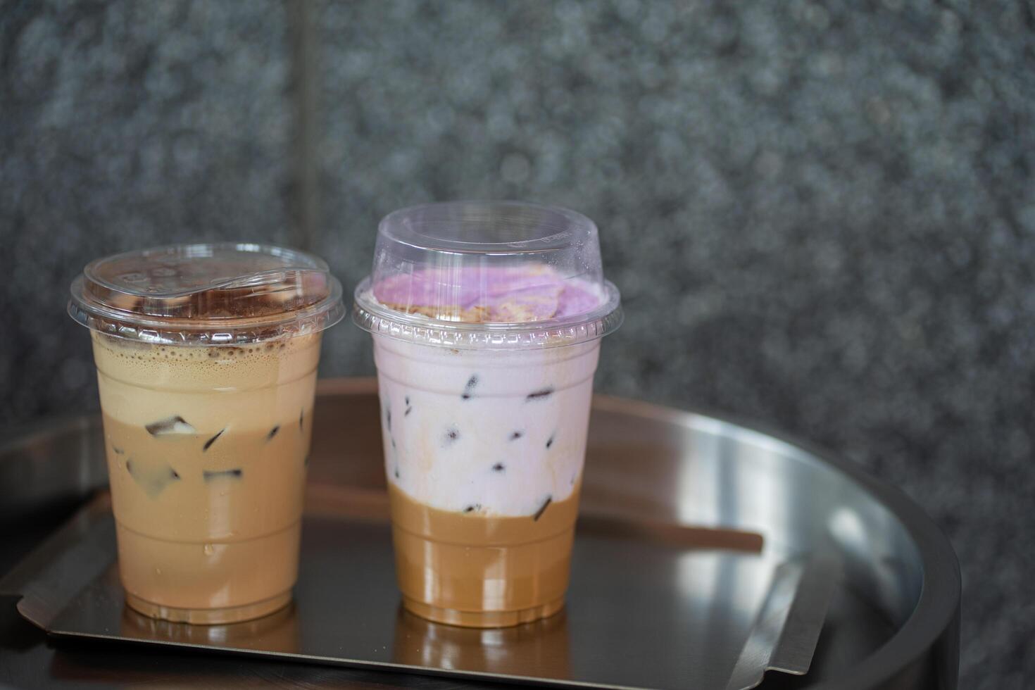 Close up glass of ice coffee with taro milk and ice cappucino on raw cement table of a coffee shop summer terrace, menu photography. photo