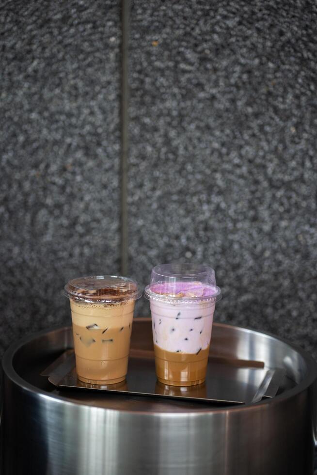 Close up glass of ice coffee with taro milk and ice cappucino on raw cement table of a coffee shop summer terrace, menu photography. photo