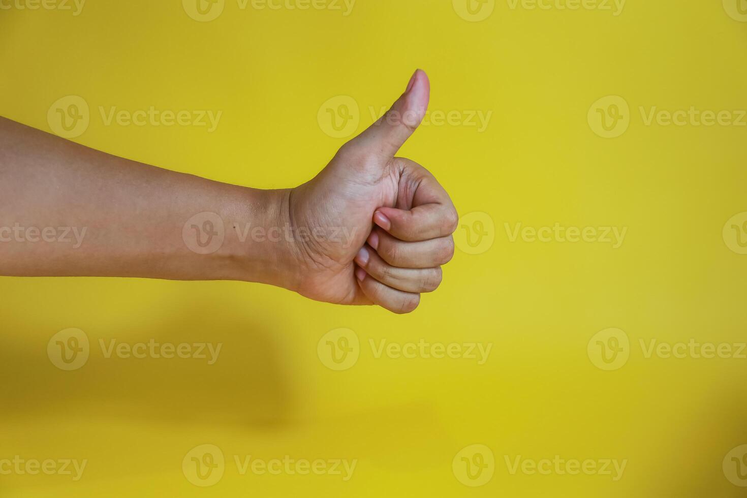 hand with thumb up isolated on yellow background photo