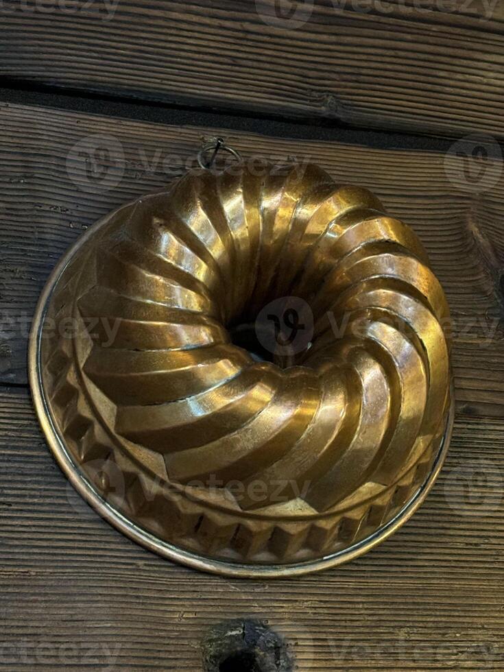 Vintage brass bundt cake mold on rustic wooden background photo