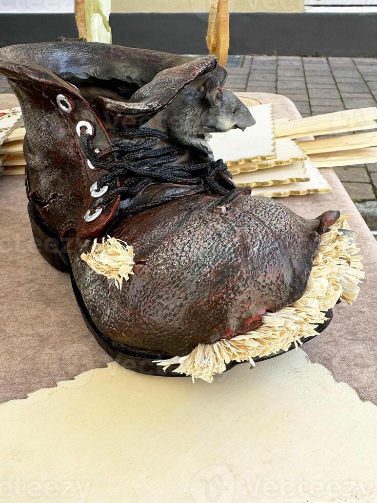 Artistic clay boot with straw details on outdoor display table photo