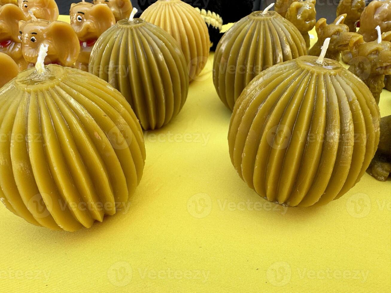 Round ribbed handmade beeswax candles on yellow background photo