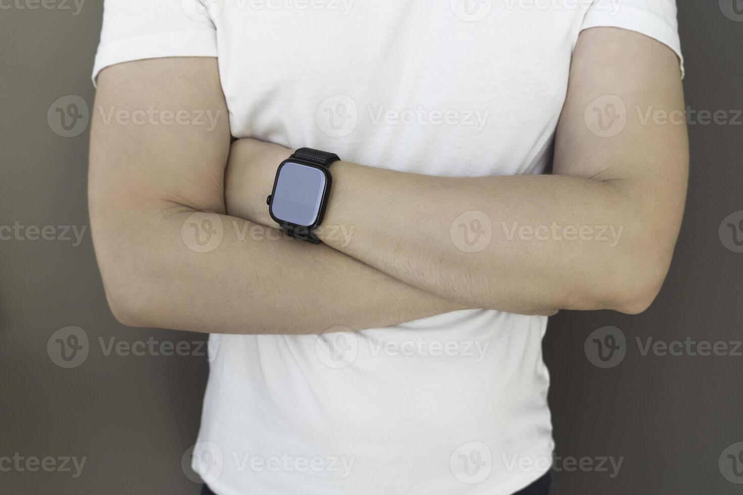 Attractive unknown man in white t-shirt sporting a smartwatch, smart watch on male hand to track sport activity, man with crossed hands photo