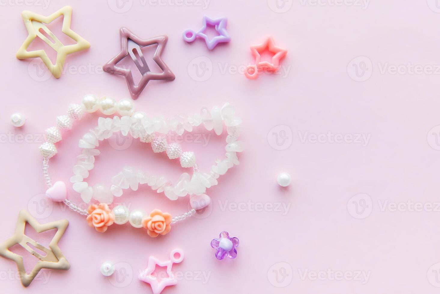 Colorful beads and charms arranged creatively on a pink background for a playful crafting session photo
