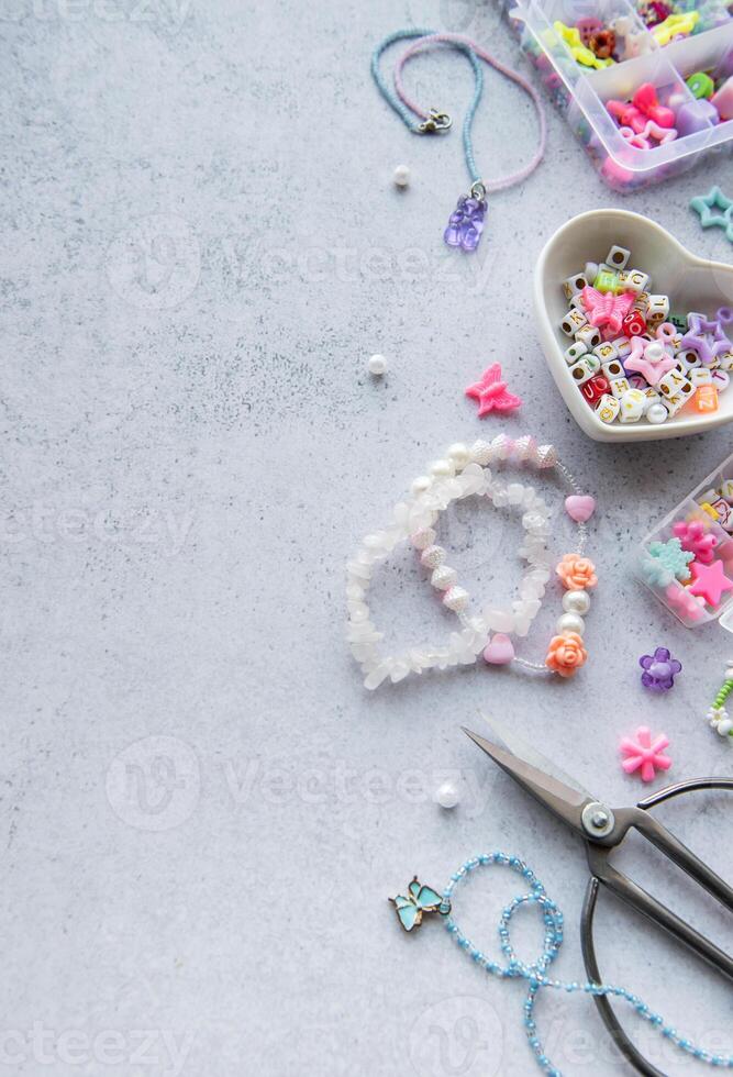 Colorful bead crafting materials arranged for creating unique jewelry pieces on a light grey surface photo