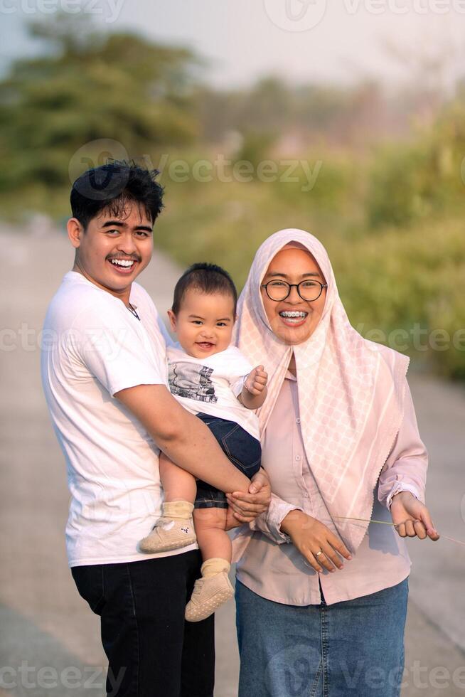 A young family that looks happy and laughing out loud with mother, father and baby boy. photo taken vertically. photo atmosphere in nature.