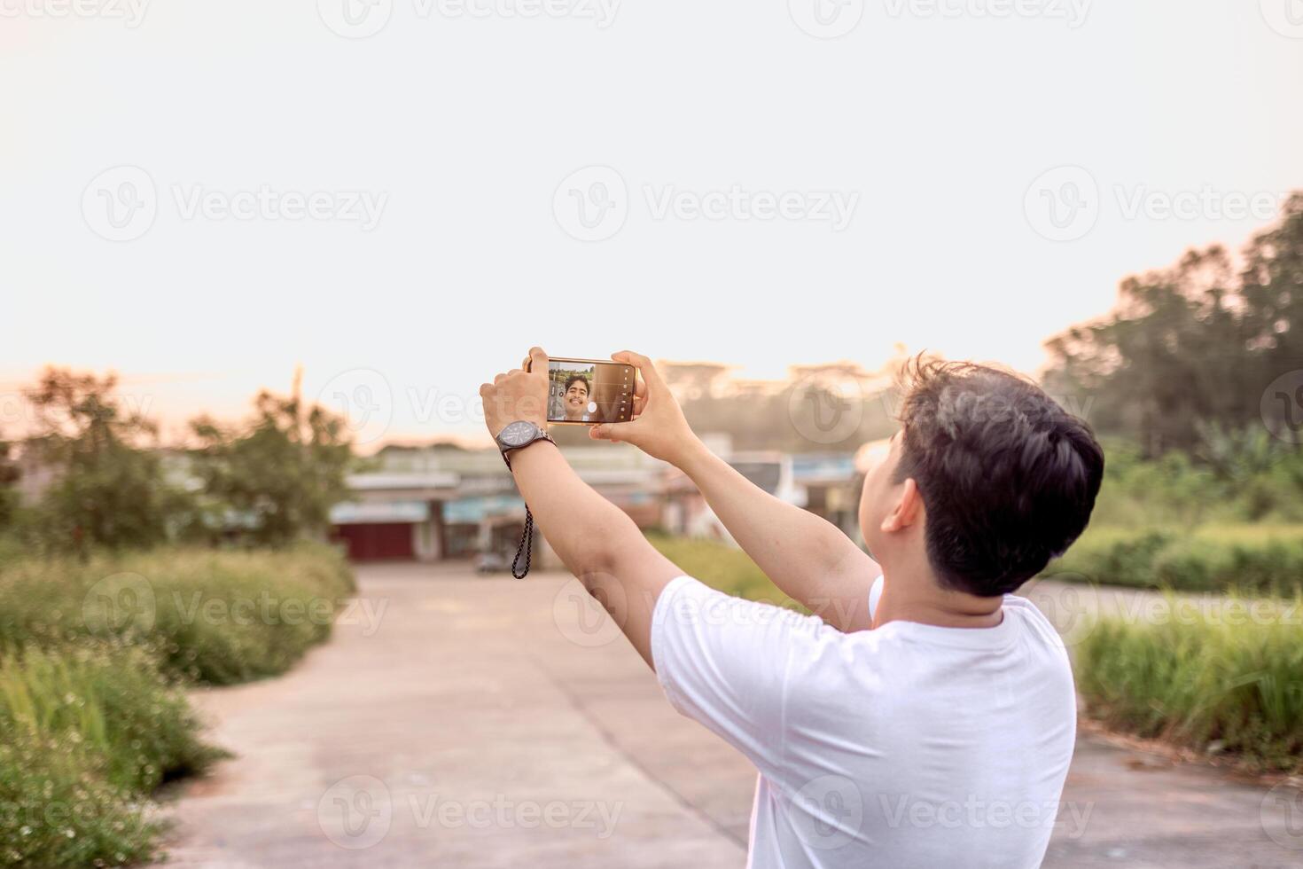 a man who is taking photos of himself and nature in various styles. the man has his back to the camera. set on a sunny afternoon in nature.
