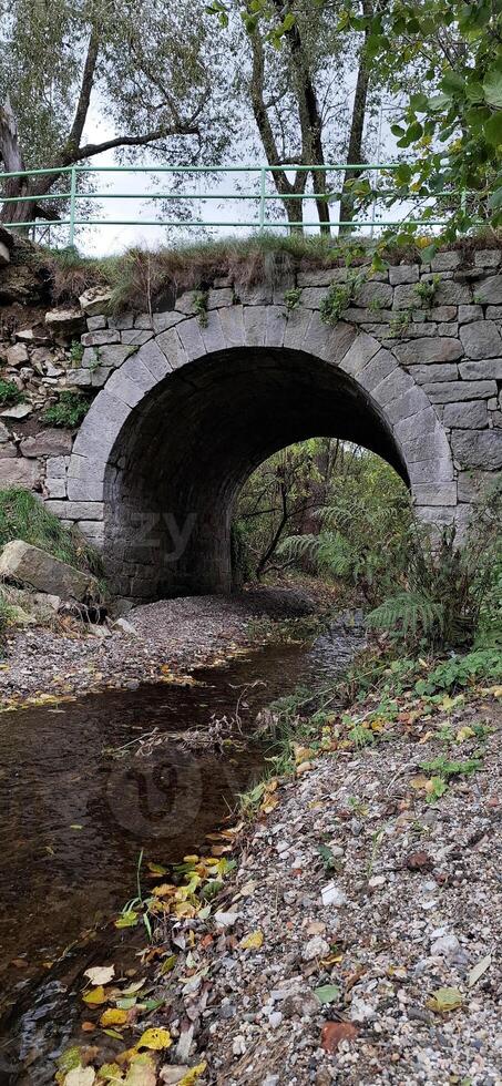 Pedestrian bridge over a tributary of the Bobr River, Jelenia Gora, Poland. Autumn landscape photo