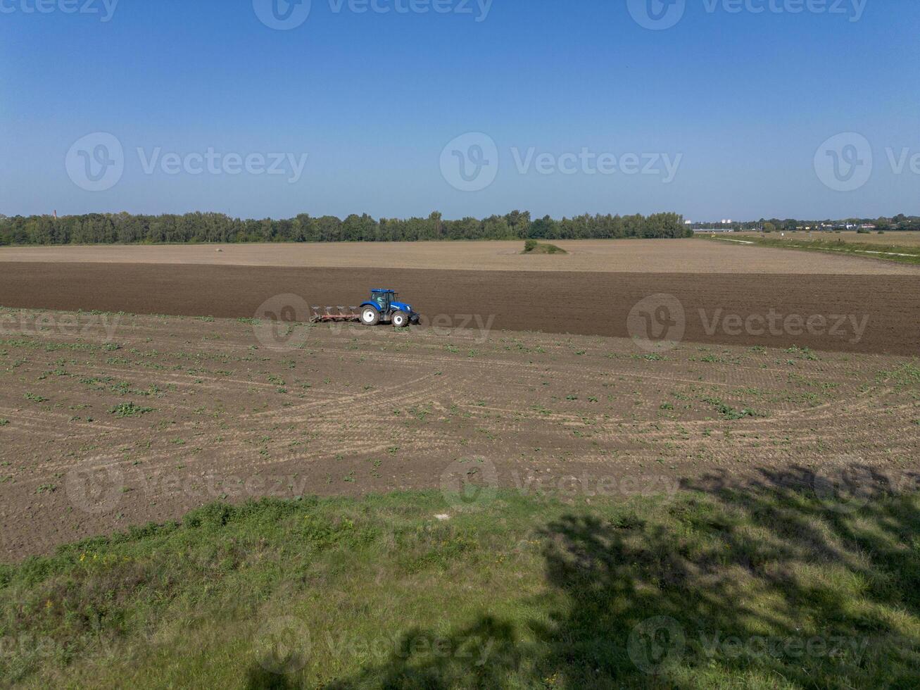 Tractor processes, plows agricultural field, top view, background. photo