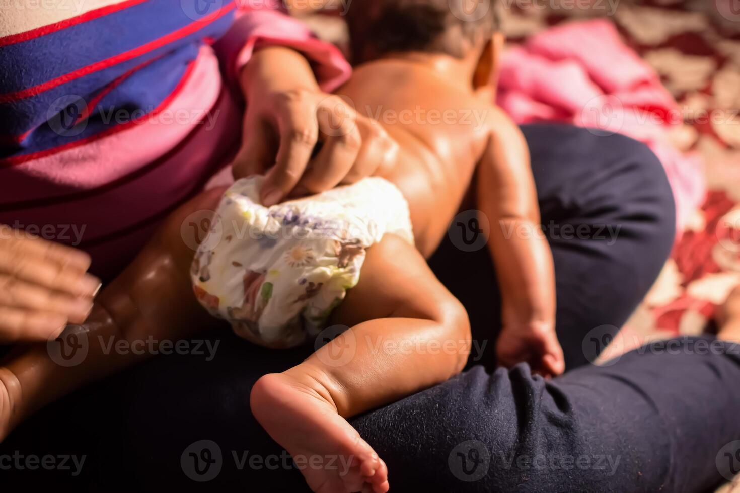 10 Months cute little Indian boy doing oil massage at home by his mother, cute little boy enjoying during oil massage, little toddler enjoying healthy massage by mother photo