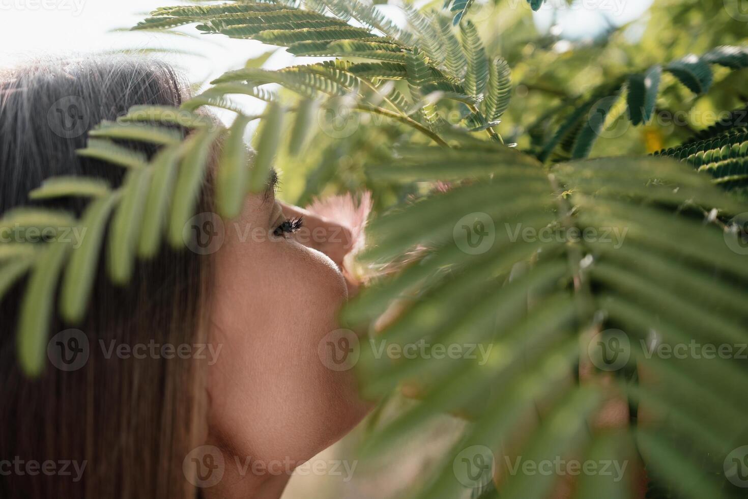Beauty portrait of happy woman closeup. Young girl smelling Chinese acacia pink blossoming flowers. Portrait of young woman in blooming spring, summer garden. Romantic vibe. Female and nature photo
