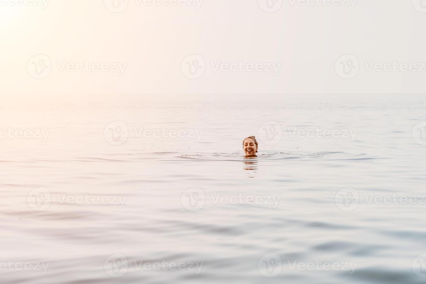 Man Water Ocean Drowning - A single man is in the water, with only his head and one arm visible. He is struggling to stay afloat and appears to be drowning. The ocean is choppy and the sky is overcast photo