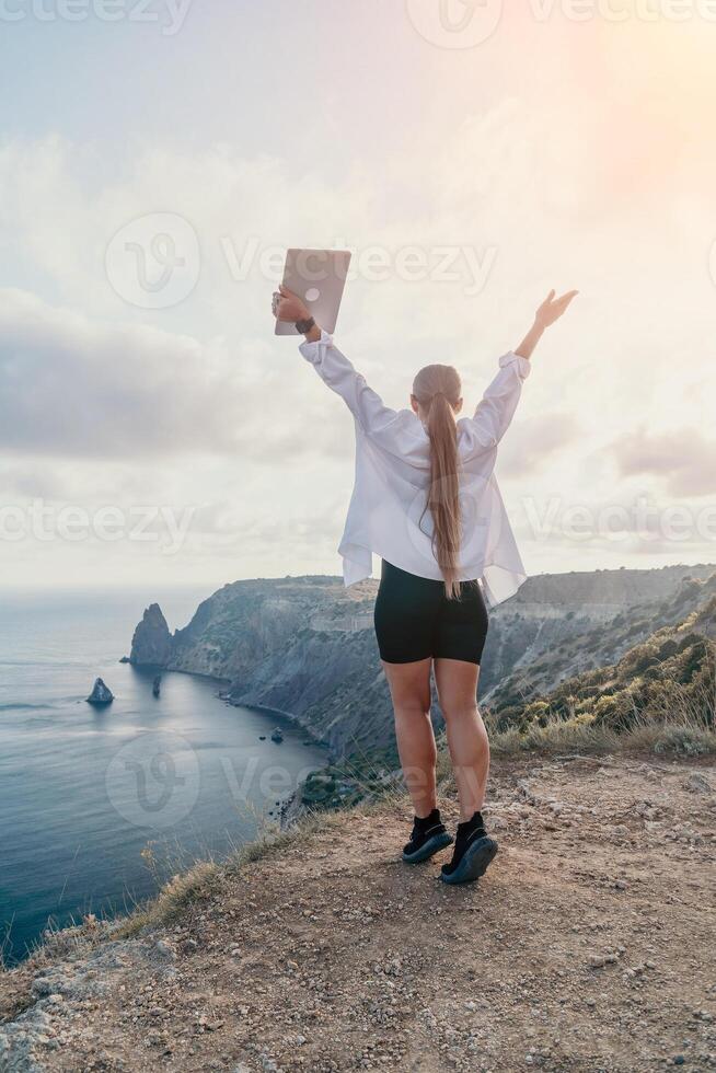 Woman Laptop Success Celebrating Achievement Cliffside Ocean Sunset Freedom Inspiration Joy Travel Adventure photo