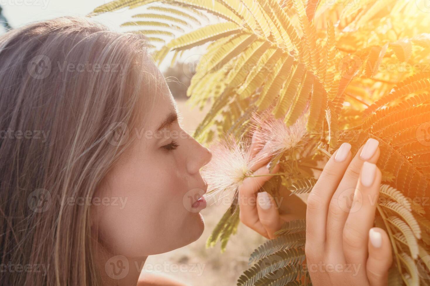 Beauty portrait of happy woman closeup. Young girl smelling Chinese acacia pink blossoming flowers. Portrait of young woman in blooming spring, summer garden. Romantic vibe. Female and nature photo