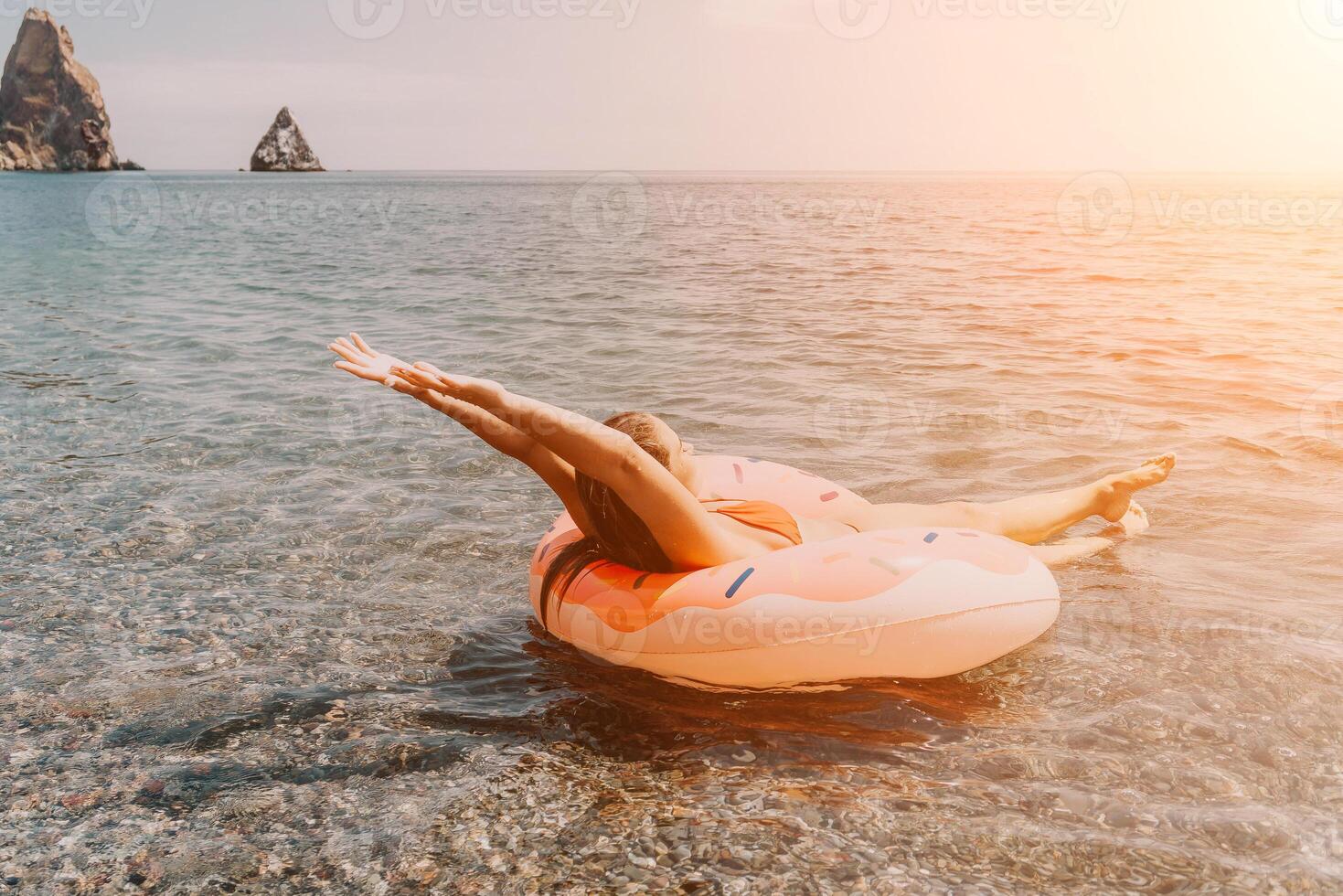 Woman, Inflatable Float, Beach. Relaxing on a pink flamingo float in the ocean during sunset. photo