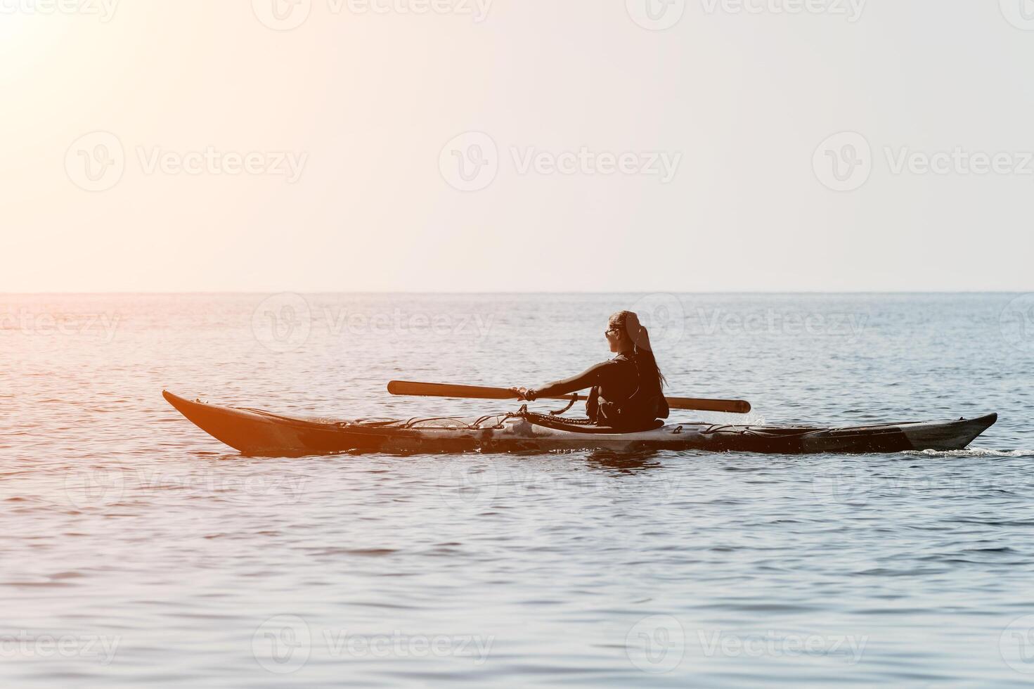 Kayaking Woman Ocean Sunset - Silhouette of woman kayaking in ocean at sunset. photo