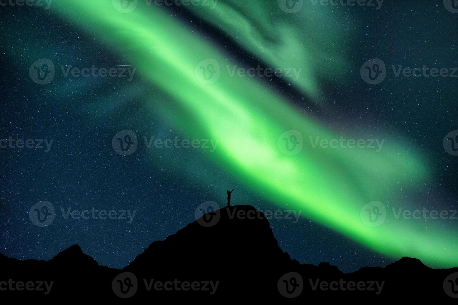 Aurora borealis with starry glowing over hiker standing on summit mountain in the night photo