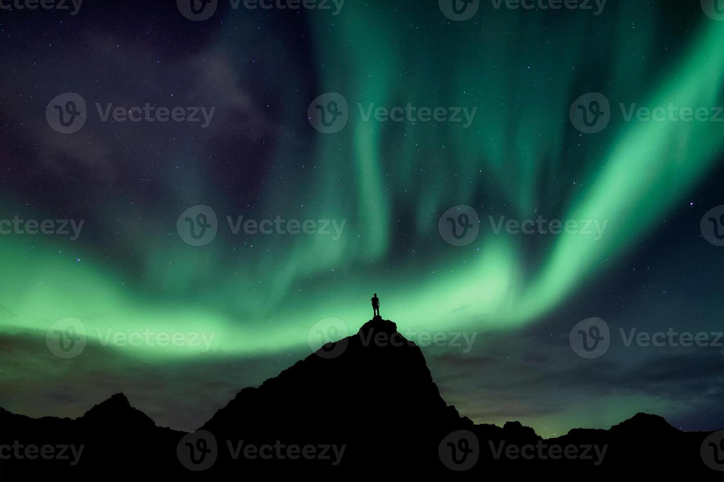 Aurora borealis with starry glowing over hiker standing on summit mountain in the night photo