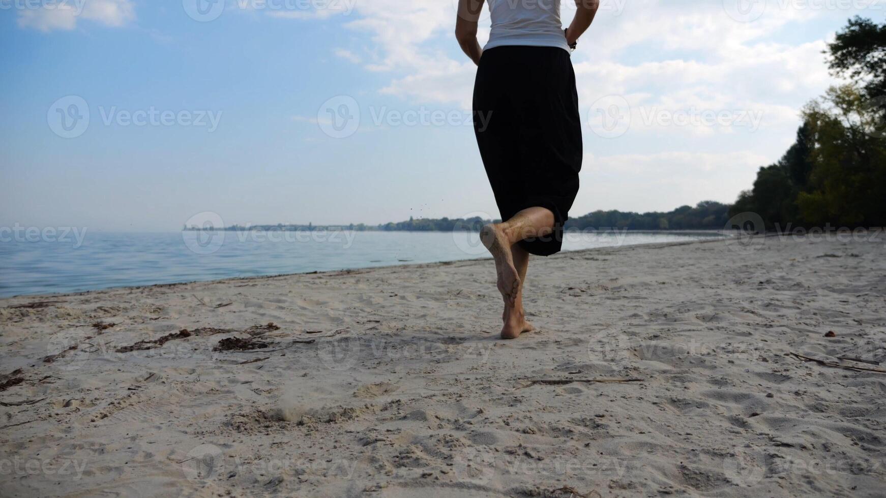 Bare feet of adult woman jogging on sand at the beach with seascape at background. Female legs running along sea shore. Happy lady spending time near ocean coast. Concept of summer vacation photo