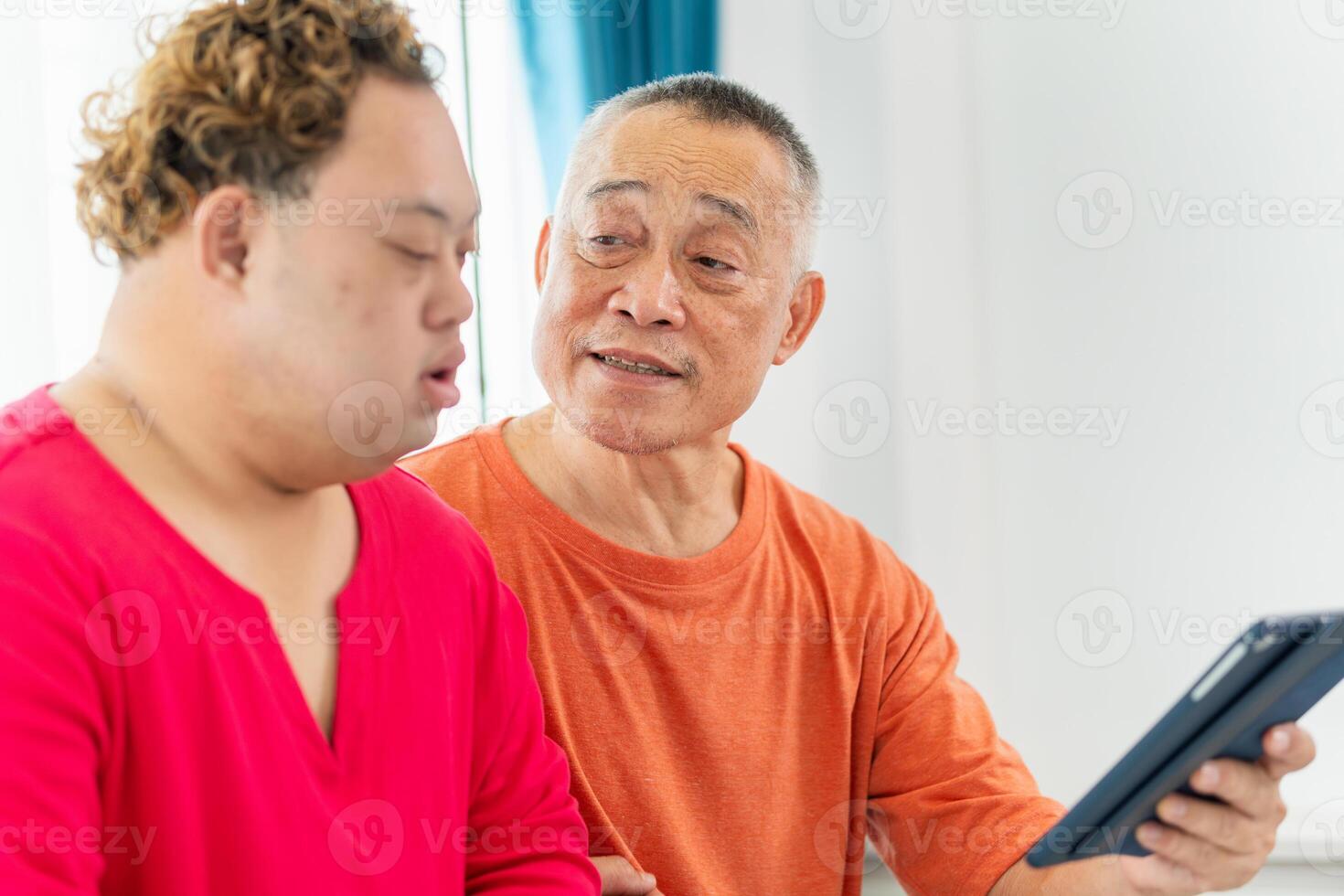 Grandfather and grandson using laptop doing a call in living room, Senior asian man having a good time sitting on couch at home with adult son photo