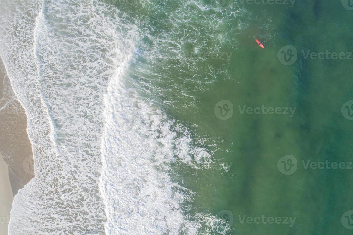 Aerial view of sandy beach and ocean with waves surfer waiting for the good wave photo