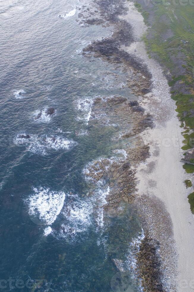 aerial view of ocean waves breaking on rocky coast photo
