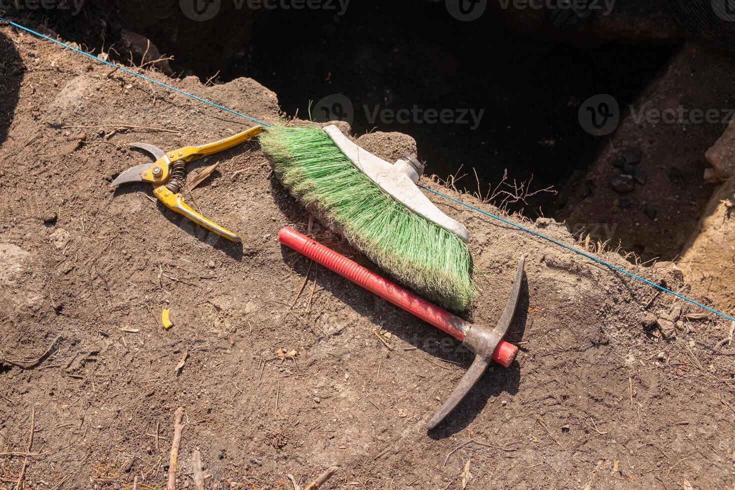 tools in an archaeological dig , pruning shears, broom and pickaxe photo