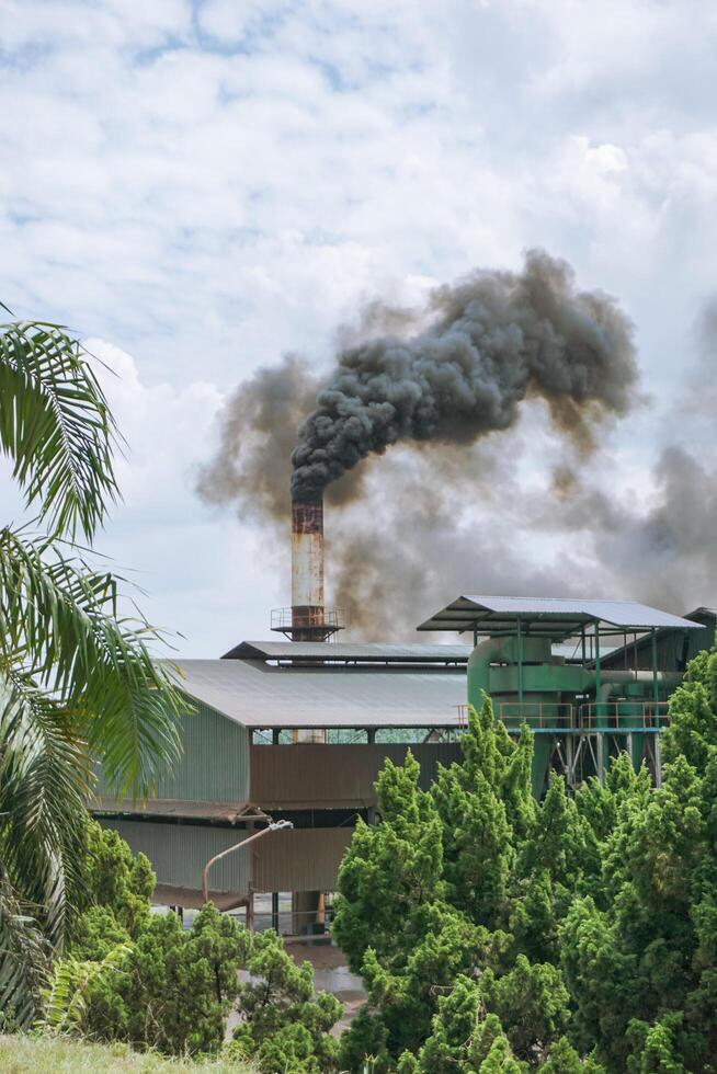 Industrial factory pollution from palm oil factory in Indonesia. Smoke coming out of the chimneys at the sunny day photo
