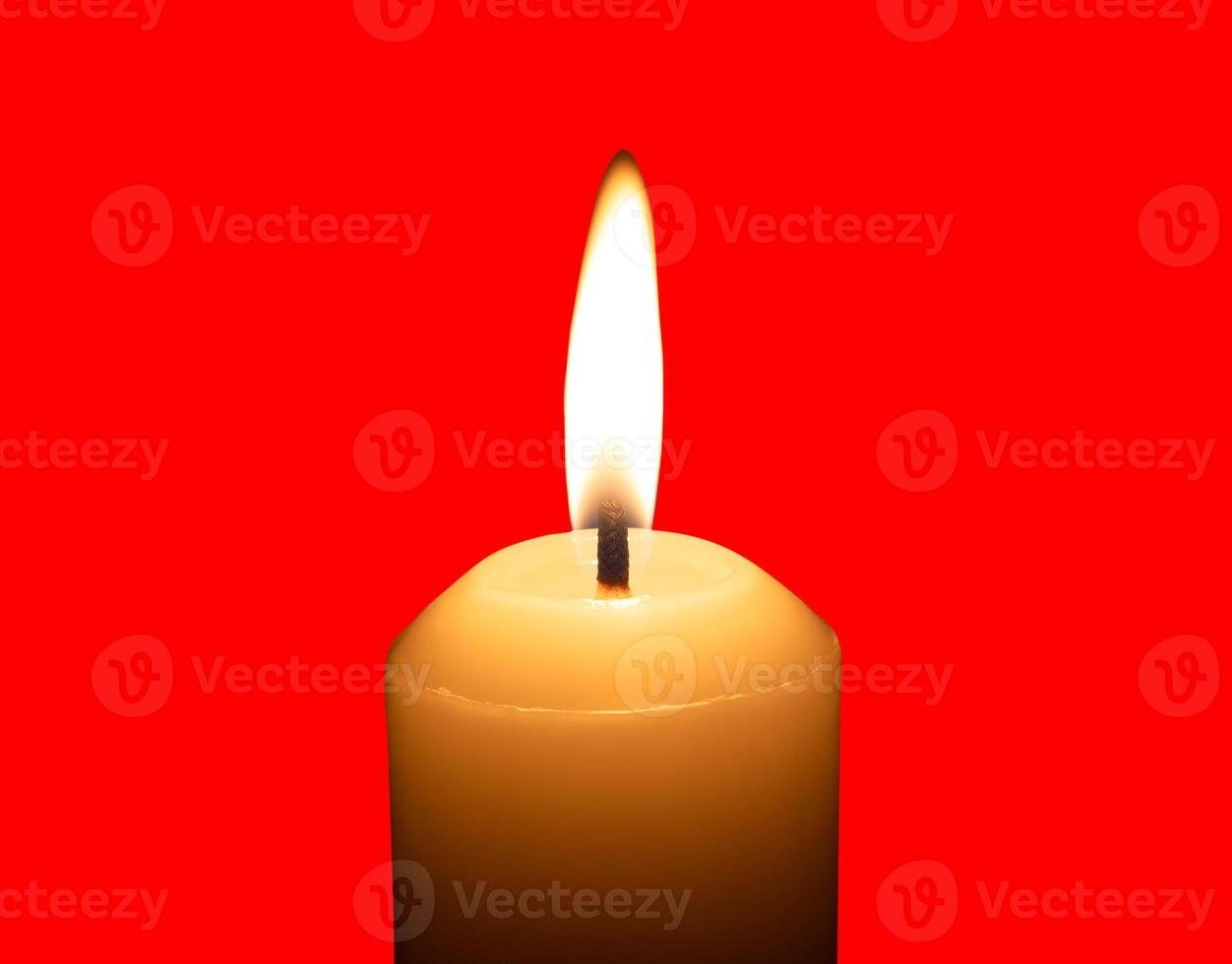 A single burning candle flame or light glowing on a big white candle isolated on red background with clipping path photo