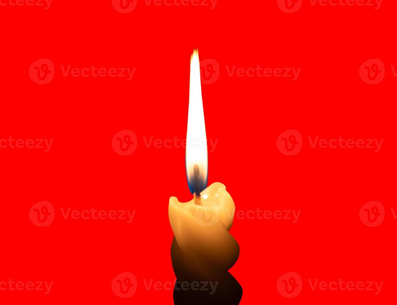 A single burning candle flame or light glowing on a small spiral white candle isolated on red background with clipping path photo