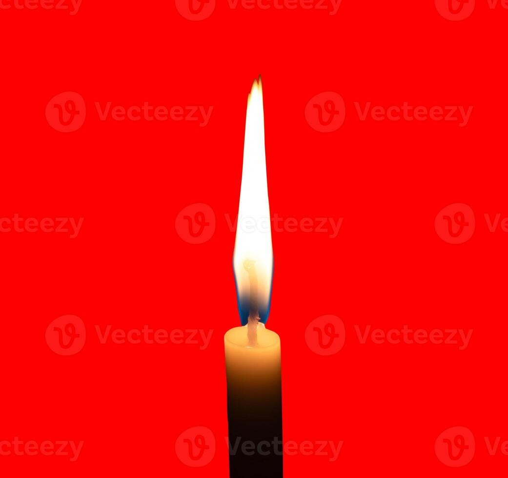 A single burning candle flame or light glowing on a small white candle isolated on red background with clipping path photo