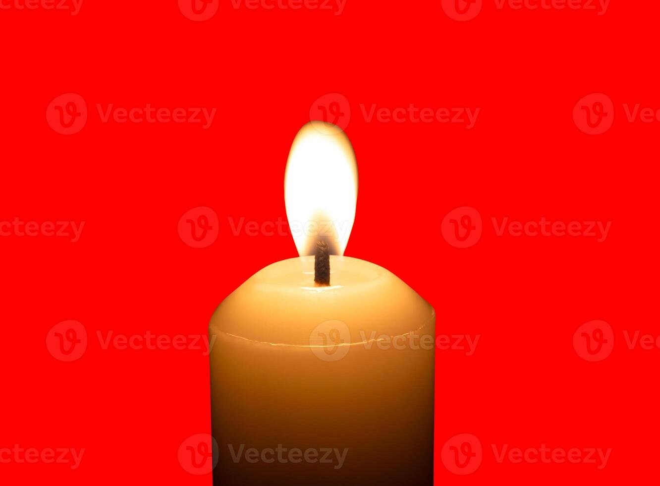A single burning candle flame or light glowing on a big white candle isolated on red background with clipping path photo