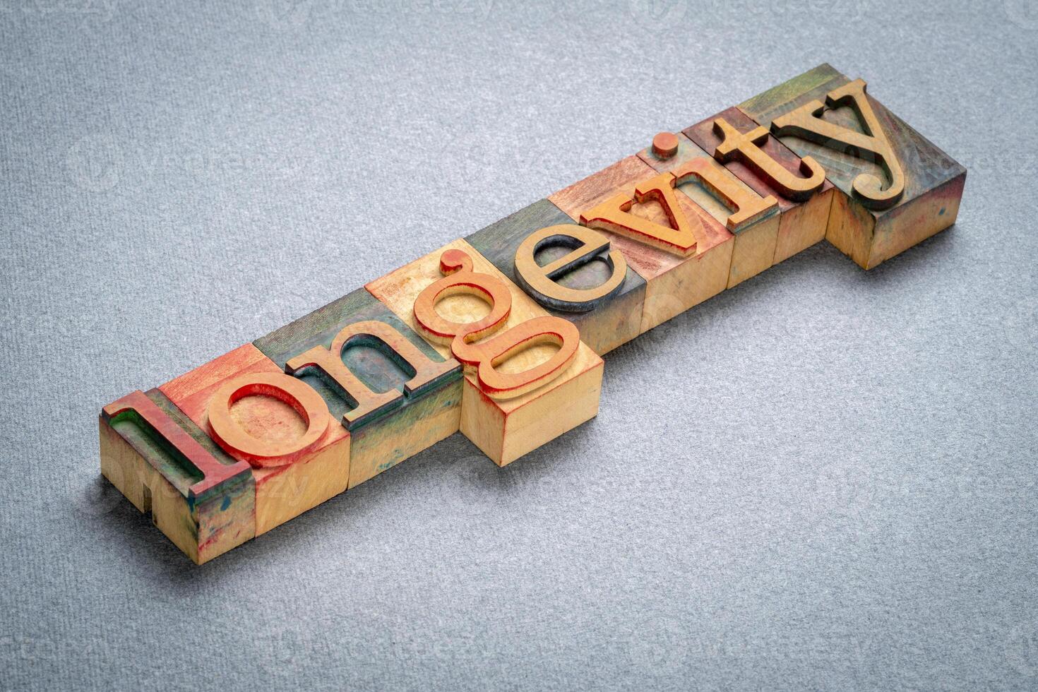 longevity text in retro letterpress wood type stained by color inks, lifespan and aging concept photo