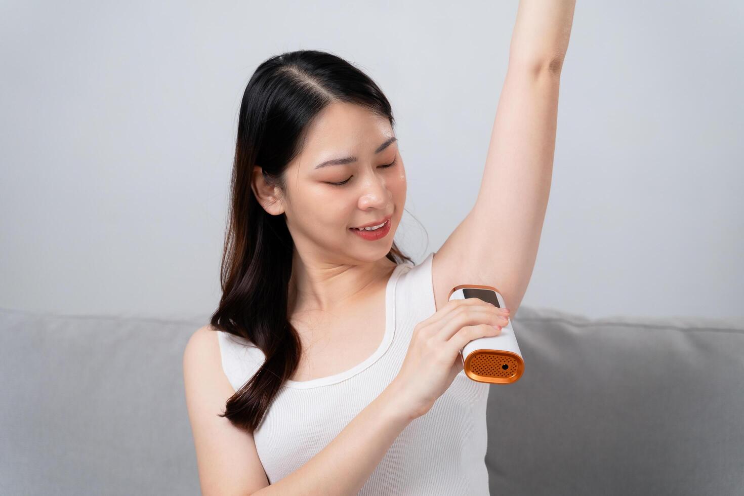 A beautiful woman is epilating her armpits using an IPL laser hair removal epilator device photo