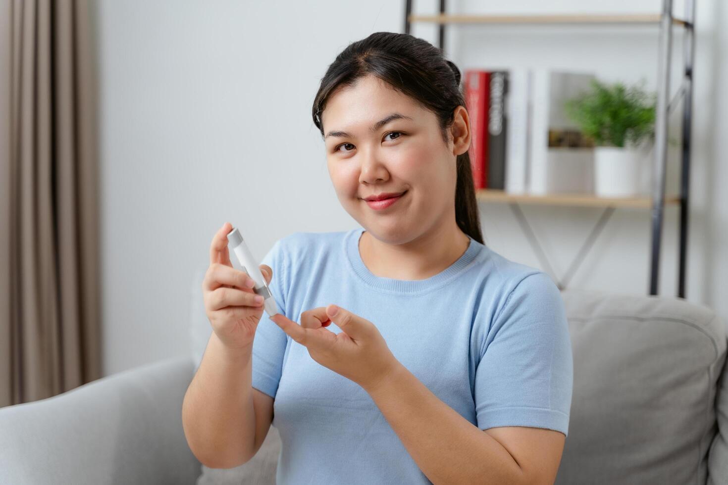 A woman is sitting on a couch and holding a blood glucose meter photo