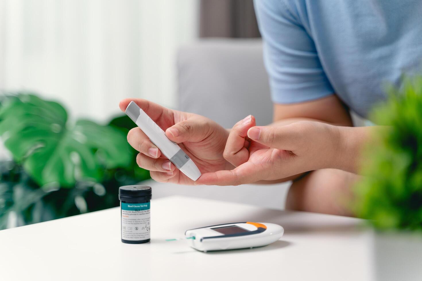 Asian woman using lancet on finger for checking blood sugar level by Glucose meter photo