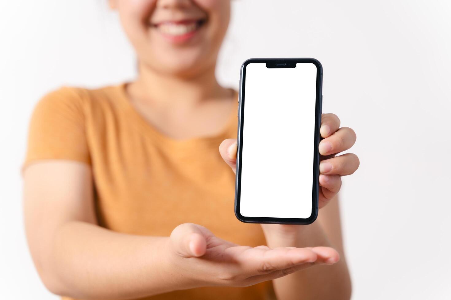A woman is holding a blank empty white screen smart phone in her hand and smiling photo