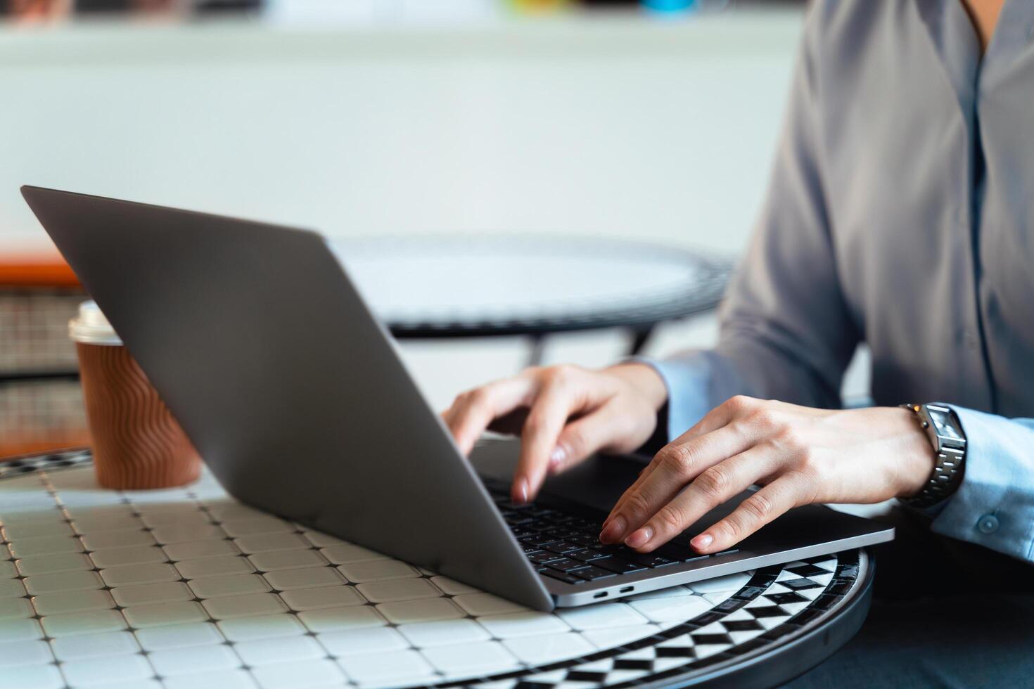 A woman is typing on a laptop at a table with a cup of coffee photo