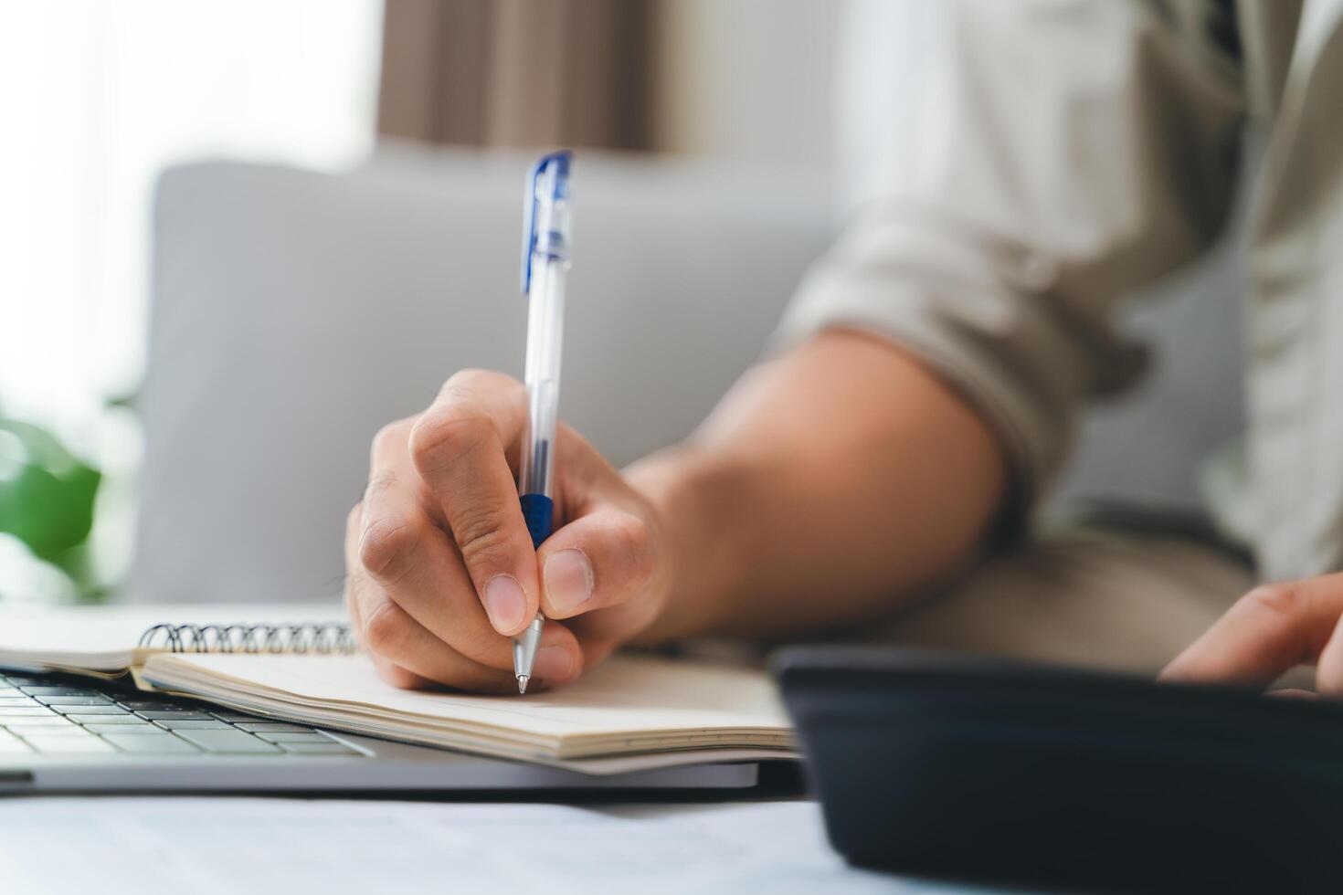 A person is writing in a notebook with a pen photo