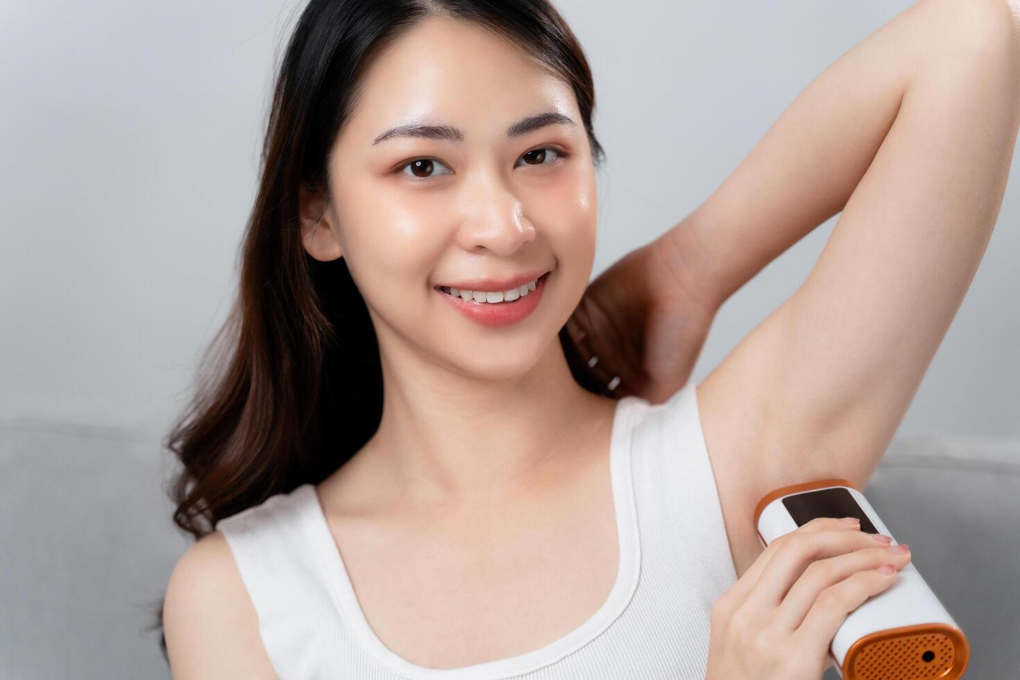 A beautiful woman is epilating her armpits using an IPL laser hair removal epilator device photo