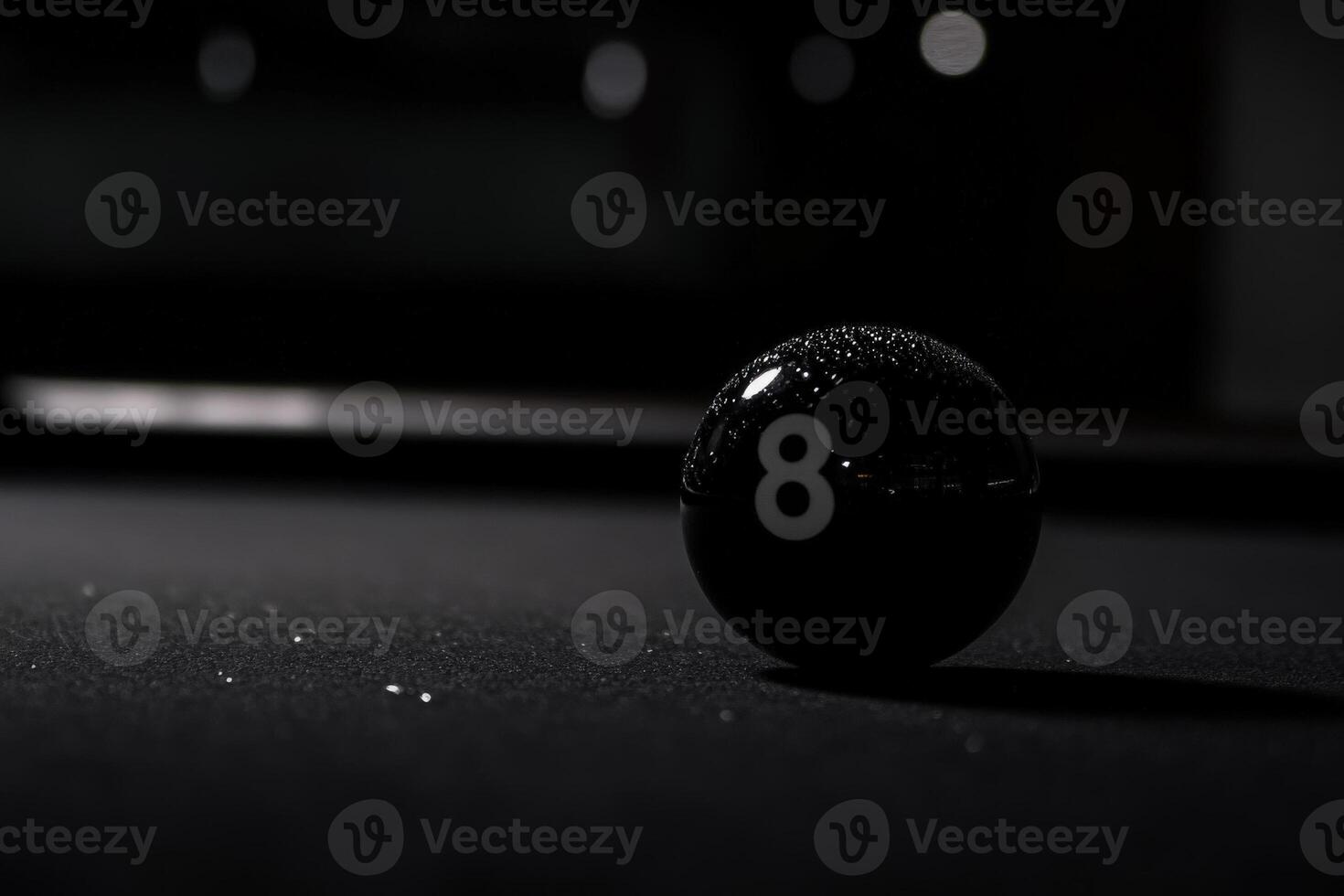 A solitary black snooker ball rests on a dark table, adorned with a single droplet of water. Soft lighting accentuates its smooth surface, highlighting the balls iconic number. photo