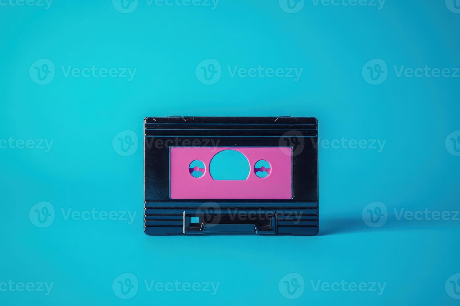 A vintage cassette tape sits alone against a vibrant turquoise background. The tape features a striking neon pink label, creating a nostalgic and colorful contrast in this retro-inspired setting. photo
