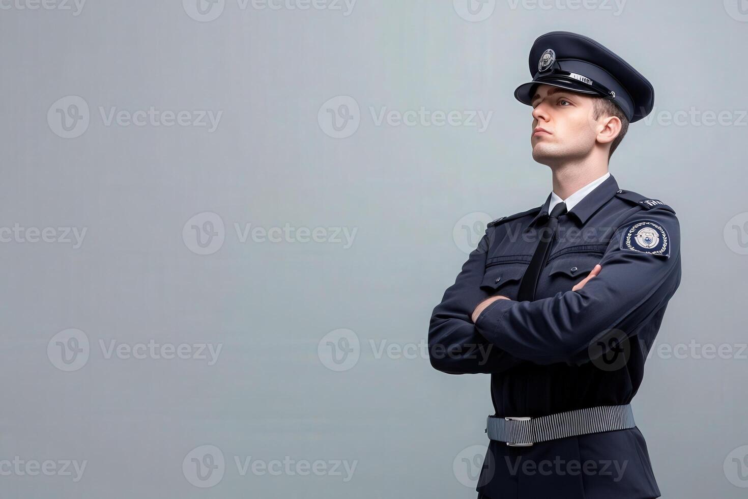 A border control officer is posed with arms crossed, displaying a sense of authority and professionalism. The backdrop is solid and clean, highlighting the officers uniform and demeanor. photo